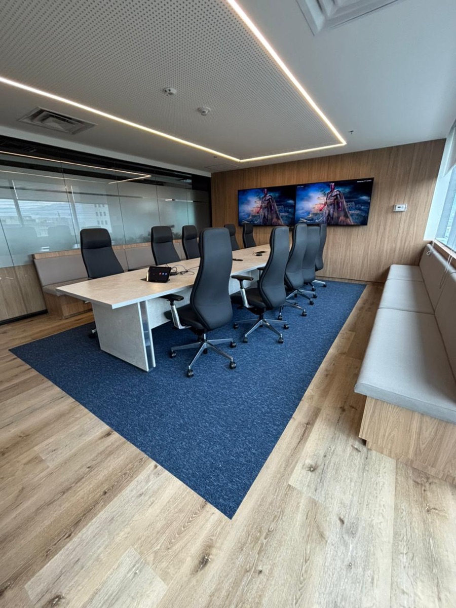 Sala de juntas con bloque de alfombra modular Flow en azul marino sobre piso de madera