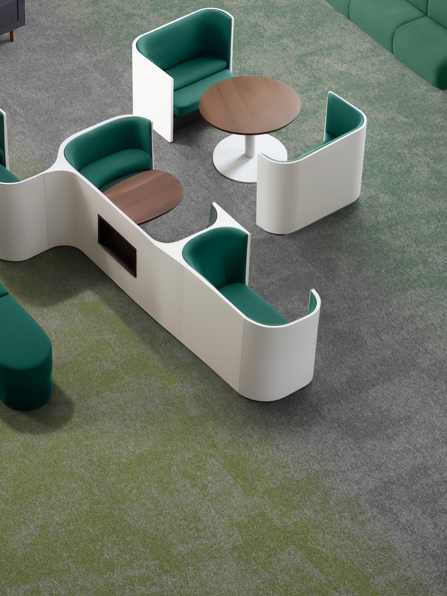 Zona de estar con módulos de asiento verdes y blancos sobre alfombra modular Glory en tono verde